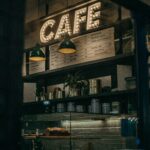 Warm and inviting cafe interior showcasing a decorative illuminated sign and shelves filled with items.